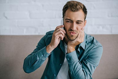 man calling the dentist because of tooth pain