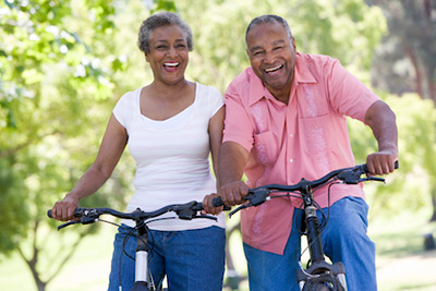 man with dental implants riding bikes with his wife