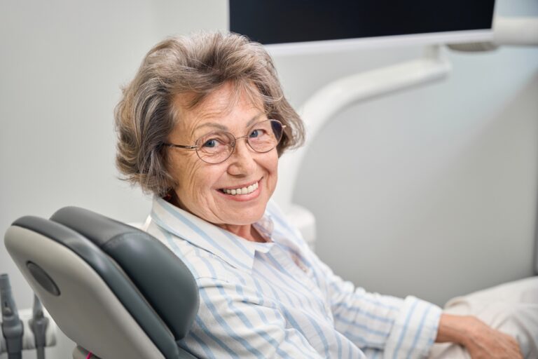 Gray-haired elderly woman sits in a dentists chair